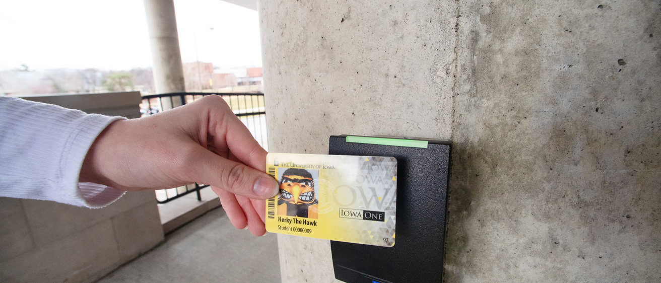 A person scans their IowaOne card to enter a building.
