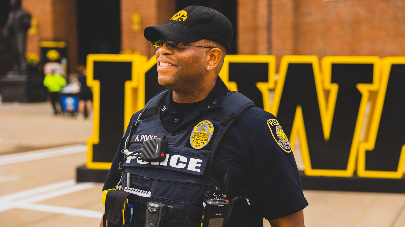 Officer Poole poses in front of a block Iowa sign near Kinnick Stadium.
